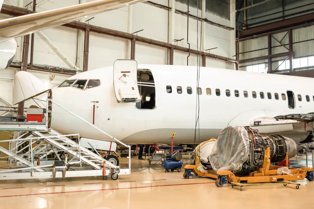 Aircraft undergoing maintenance inside MRO hangar with tools and repair equipment.